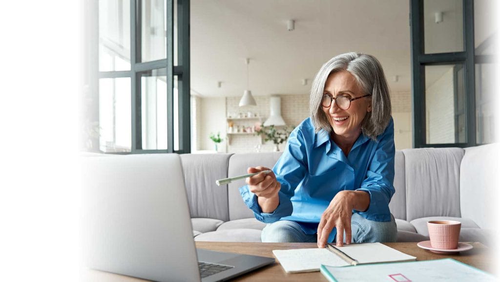 Smiling mature older woman video calling on laptop working from home